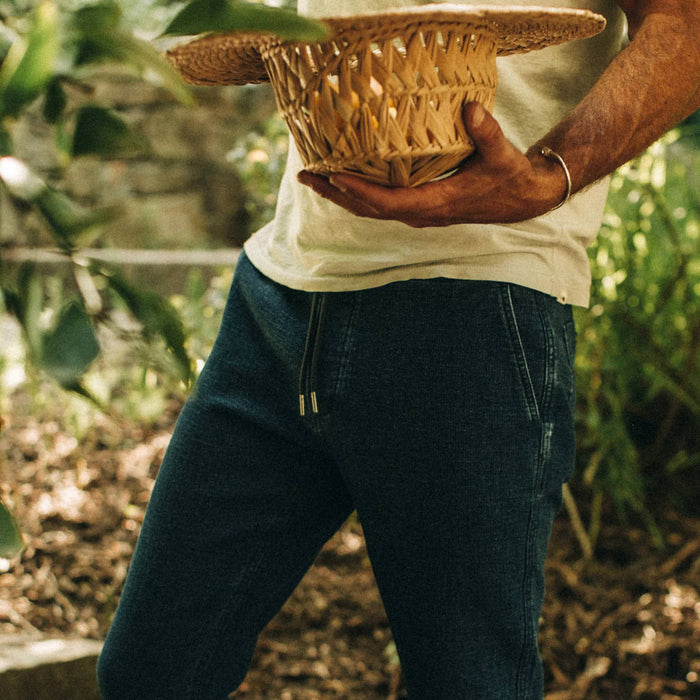 fit model wearing The Apres Pant in Indigo, holding hat