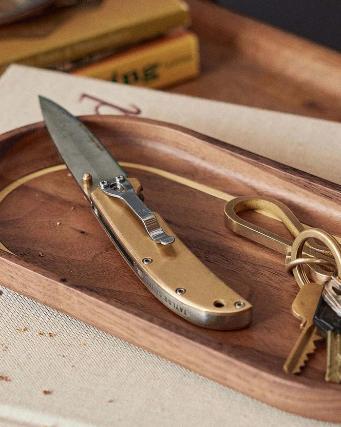 The Drop Point Knife in Brass on the valet tray