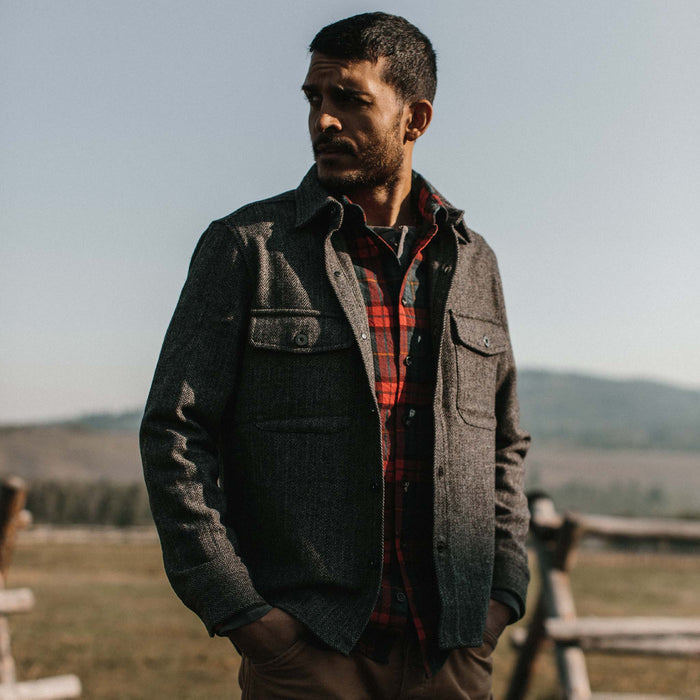 fit model wearing The Explorer Shirt in Coal Herringbone Wool looking over his right shoulder in a Wyoming field