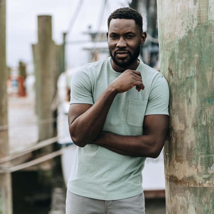 fit model leaning against a pole wearing The Heavy Bag Tee in Slate