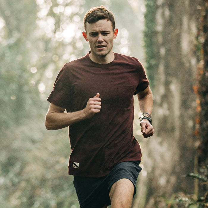fit model wearing The Merino Tee in Wine, running in woods