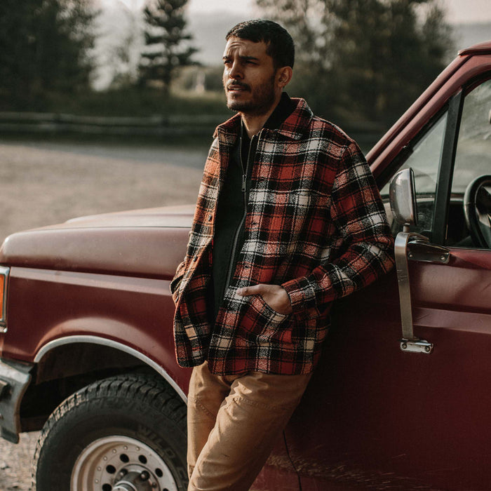 fit model wearing jacket with hands in pockets leaning up against red truck