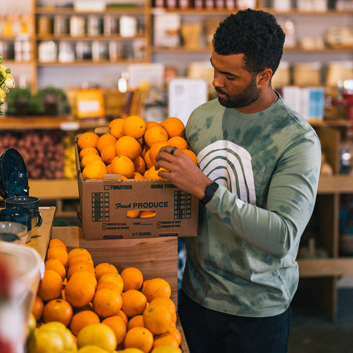 fit model holding a crate of oranges in The Organic Cotton Long Sleeve in Ecology Center