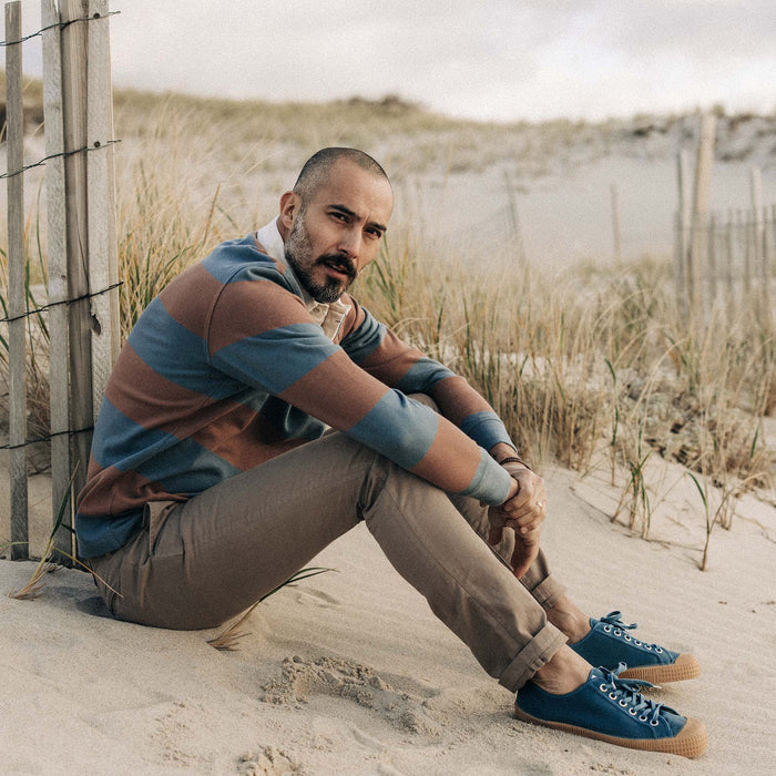 fit model sitting on the beach in The Rugby Shirt in Faded Brick Stripe