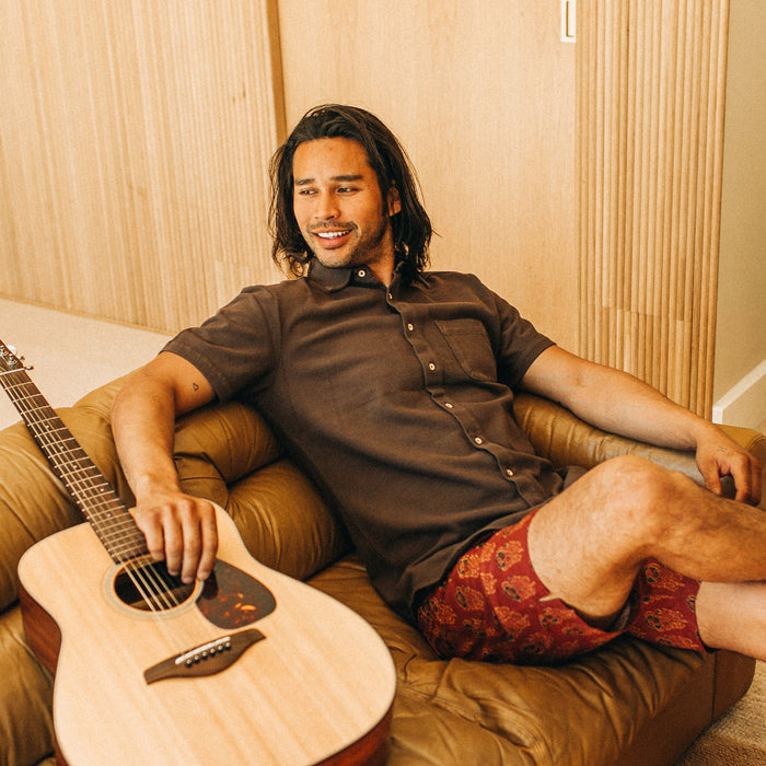 fit model sitting on a couch in The Short Sleeve California in Espresso Pique