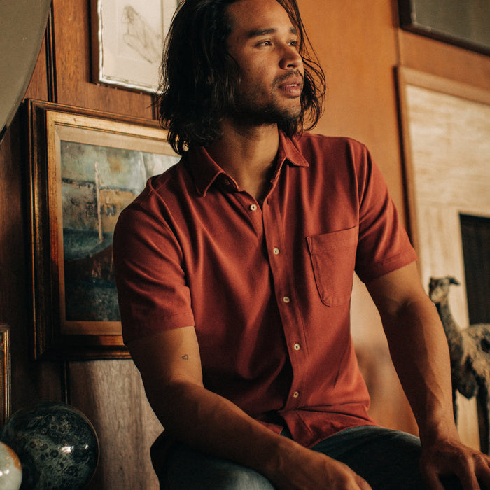 fit model sitting in The Short Sleeve California in Red Clay Pique