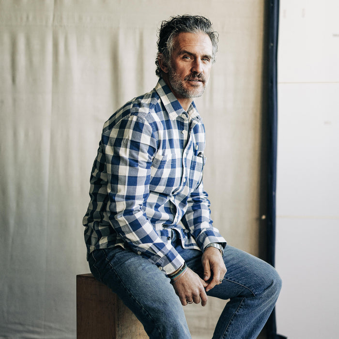 fit model sitting wearing The Utility Shirt in Sun Bleached Indigo Check