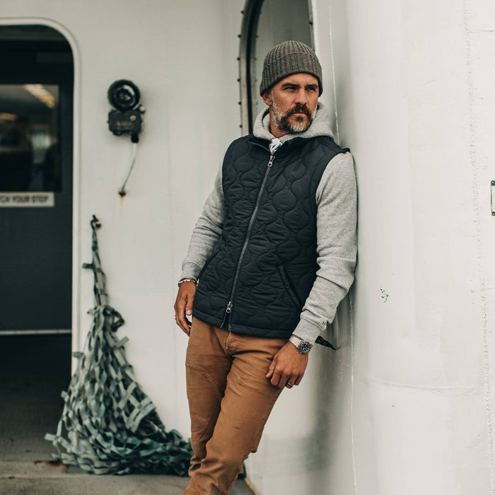 our fit model wearing The Vertical Vest in Charcoal—against a wall, looking right